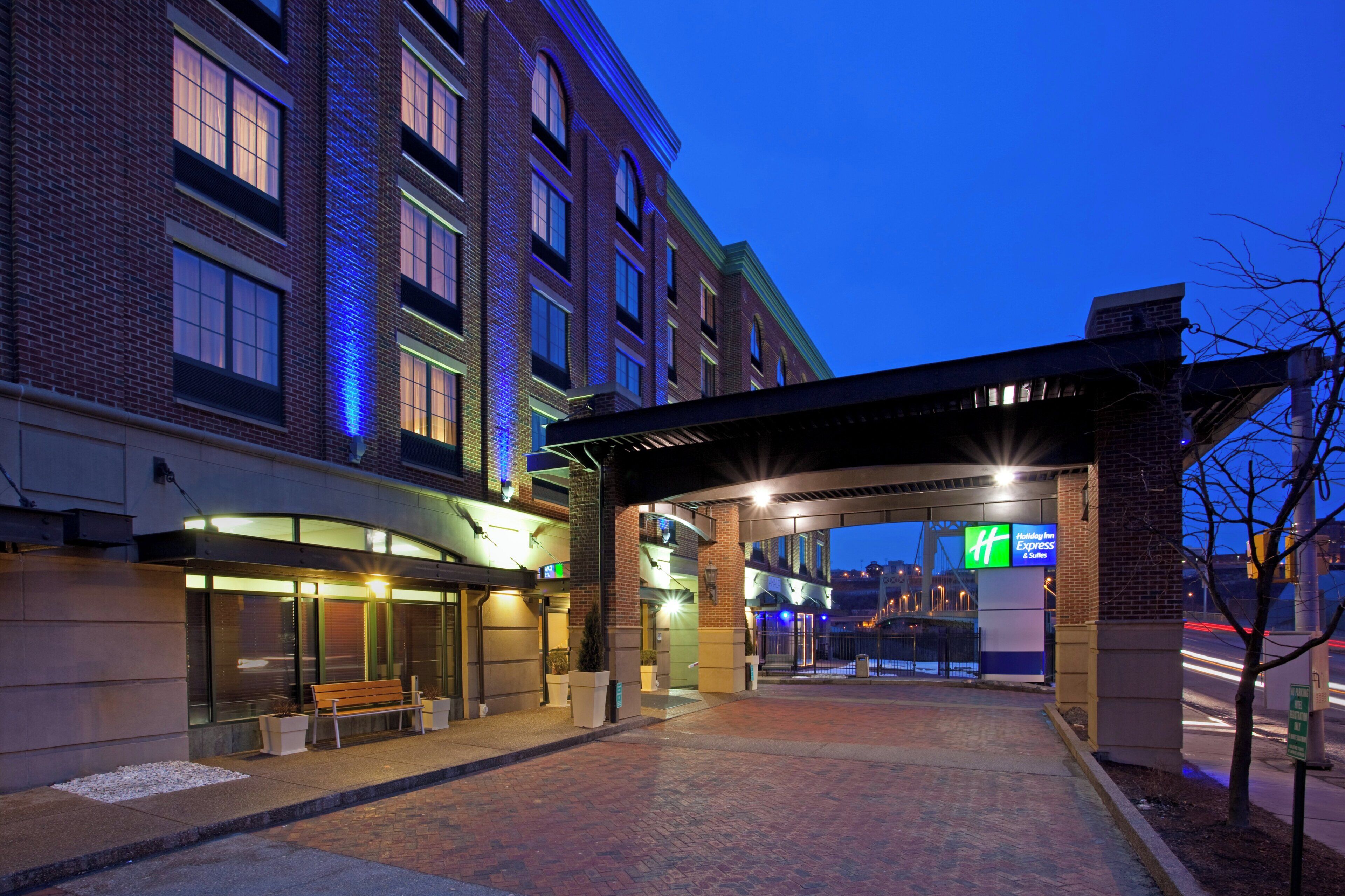 Entrada de un hotel con un corredor cubierto, un banco y un letrero de Holiday Inn Express.