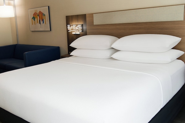 A hotel room with a large bed, a blue armchair, and a wall-mounted artwork. - Holiday Inn Express Hotel & Suites Pittsburgh-South Side by IHG (Pittsburgh)