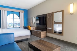 Una habitación de hotel con una cama grande, un escritorio, una silla, un aparador y un espejo.