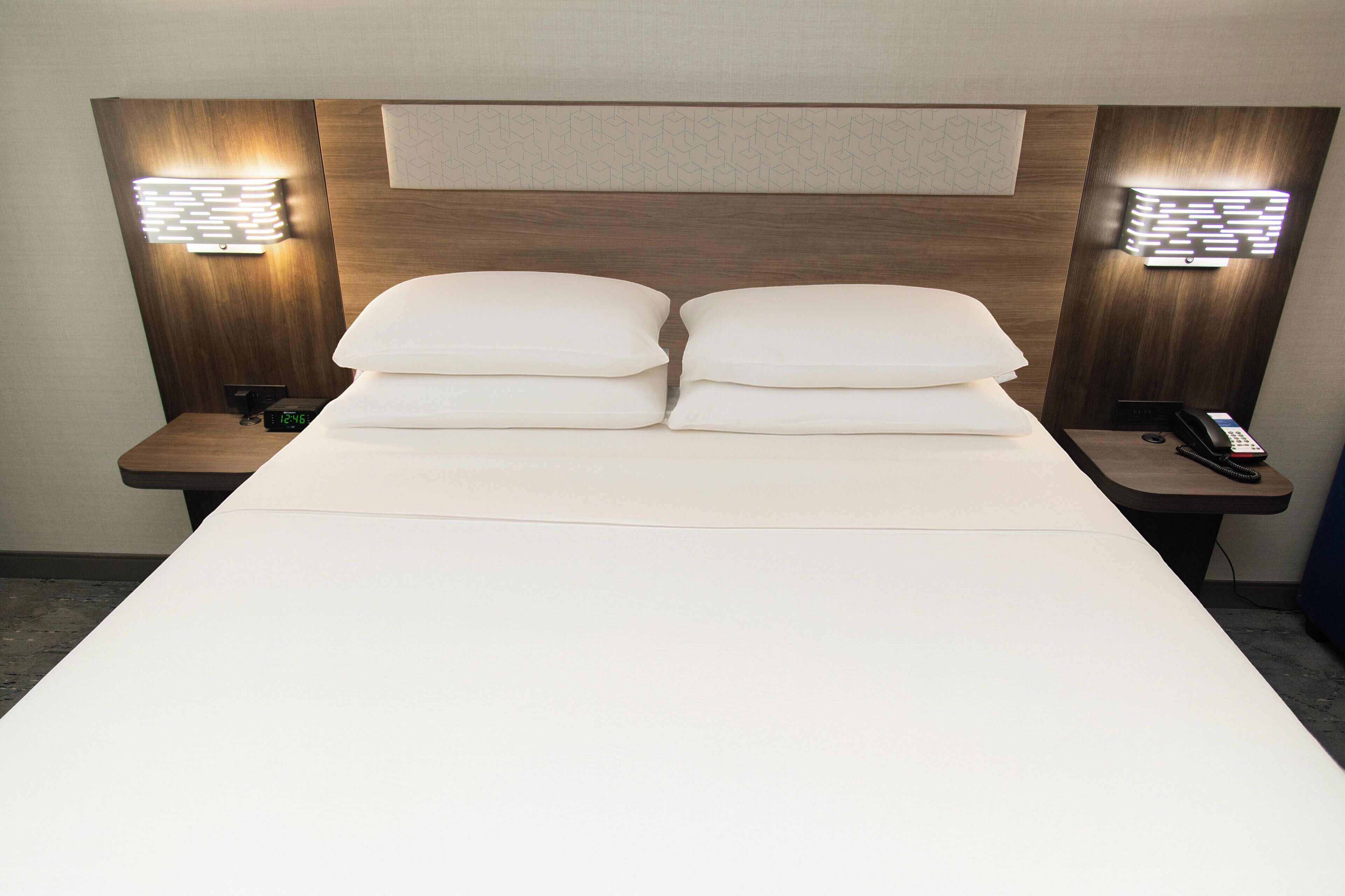 Een hotelkamer met een groot bed, twee nachtkastjes en wandlampen.