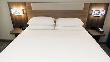 Een hotelkamer met een groot bed, twee nachtkastjes en wandlampen.