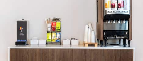 Een koffiehoek met een waterdispenser, een koffieapparaat en een theedispenser.