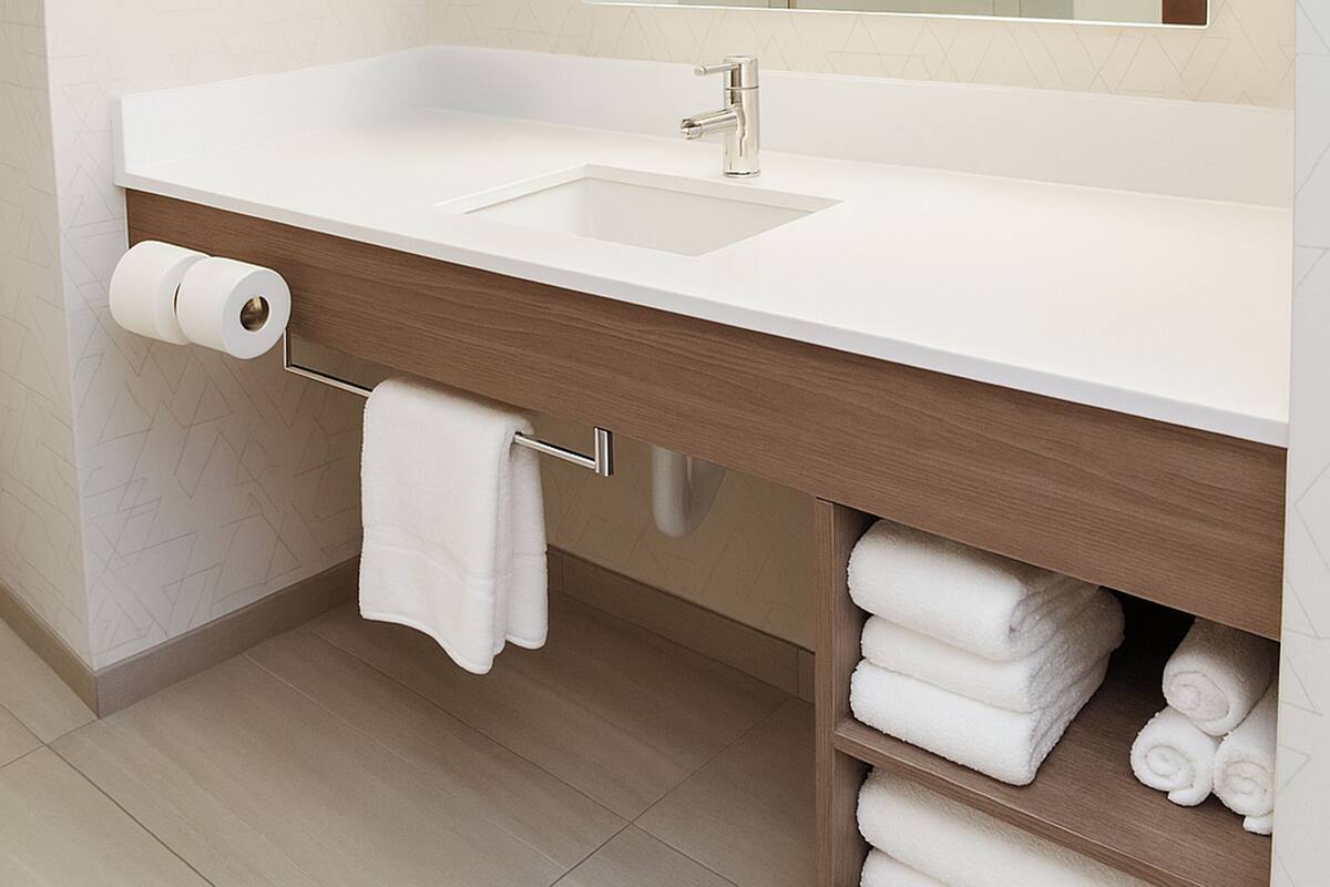 A modern bathroom with a white sink, a large mirror, and a towel rack.