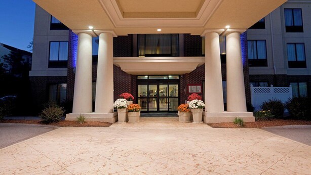 A hotel entrance with a double door, large columns, and potted plants. - Holiday Inn Express Hotel & Suites Manchester Airport by IHG (Manchester)
