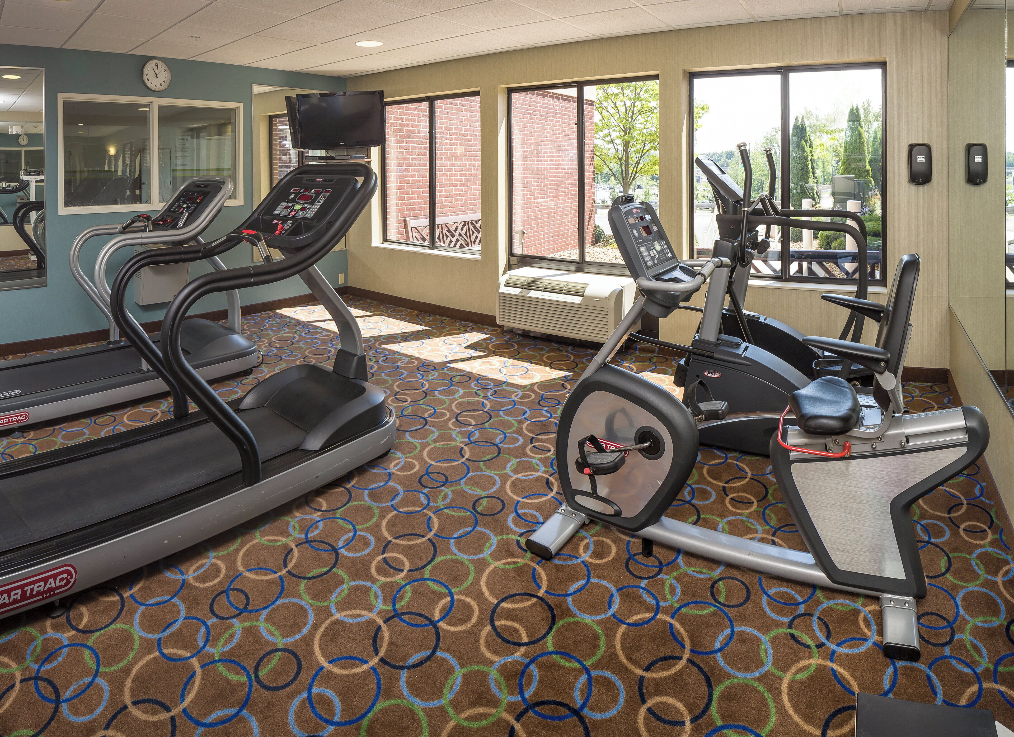 Une salle de sport équipée de tapis de course, de vélos d’appartement et d’un écran de télévision.