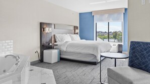 A modern hotel room with a bed, bedside table, and a view of the city through a large window. - Holiday Inn Express Hotel & Suites Manchester Airport by IHG (Manchester)