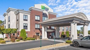 A Holiday Inn Express & Suites hotel with a brick facade, a covered entrance, and a parking lot. - Holiday Inn Express Hotel & Suites Manchester Airport by IHG (Manchester)