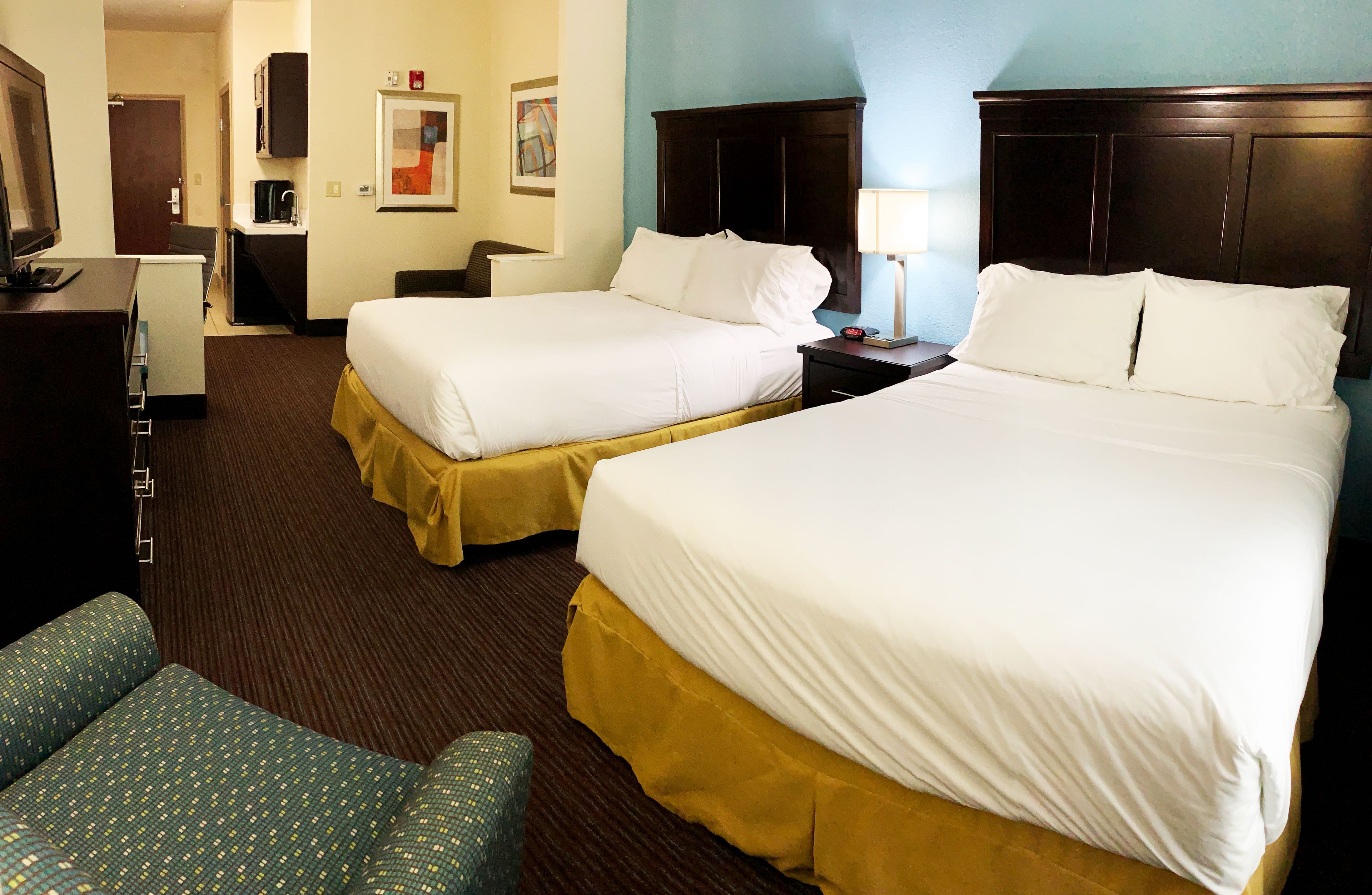 Een hotelkamer met twee bedden, een bureau, een stoel, een televisie en een koffiezetapparaat.