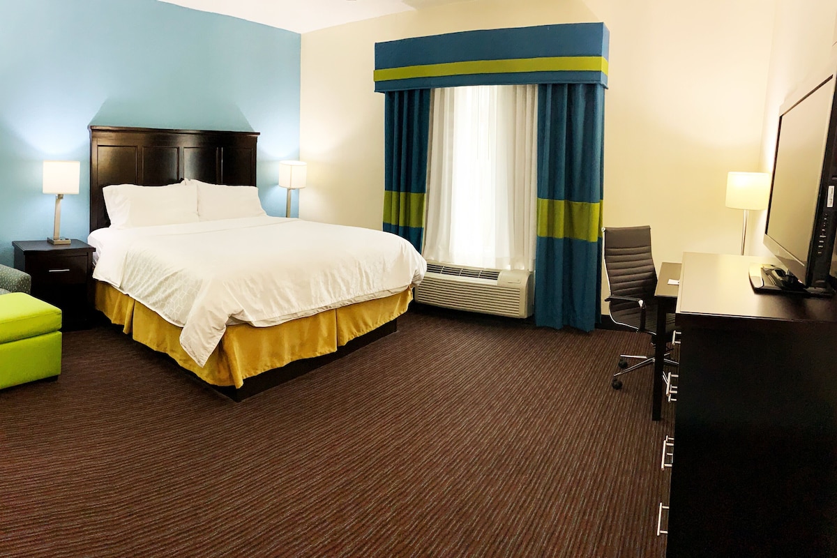 Ein Hotelzimmer mit Bett, Schreibtisch, Stuhl und Fernseher.