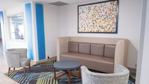 Un'area lounge moderna con un divano, due poltrone e un tavolino rotondo.