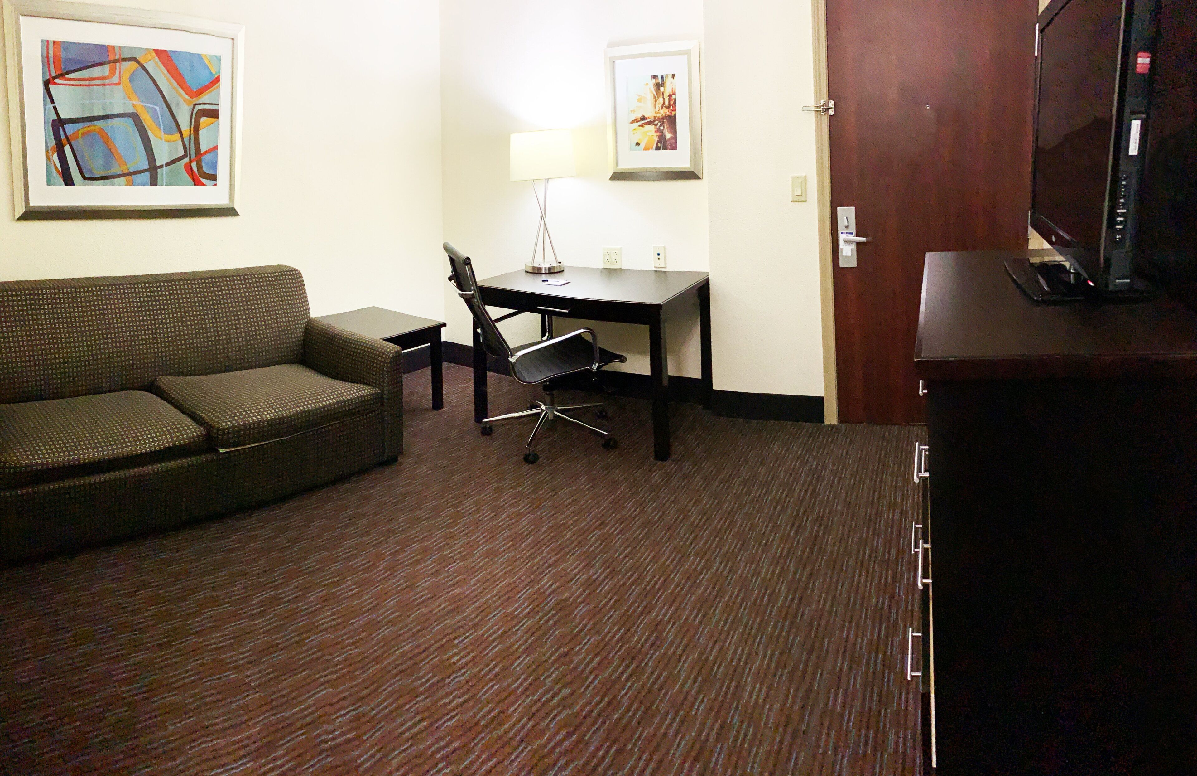 Une chambre d’hôtel équipée d’un canapé, d’un bureau, d’une chaise et d’un téléviseur.