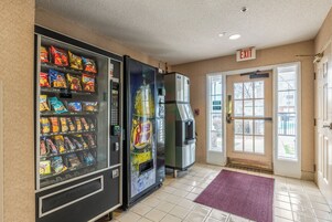 Zona de máquinas expendedoras con aperitivos y un refrigerador.