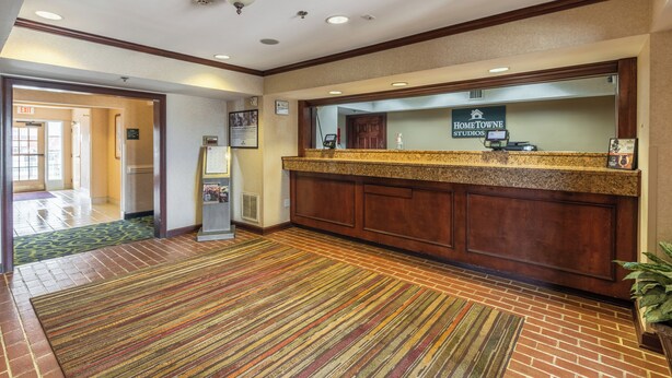 Uma área de recepção de hotel com balcão, tela digital e placa da HomeTowne Studios.