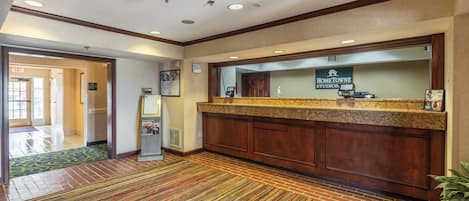 A hotel reception area with a reception desk, a digital screen, and a sign for HomeTowne Studios.