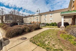 A residential building with a covered walkway, a manhole cover, and a grassy area.