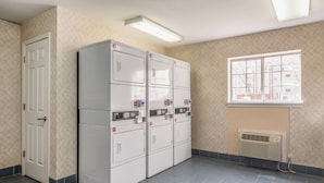 Een wasserette met gestapelde drogers, een deur, een raam en een ventilatieopening.