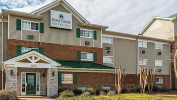 A multi-story hotel with a sign reading 'HOMETOWNE SUITES by RedRoof' and a stone facade entrance.