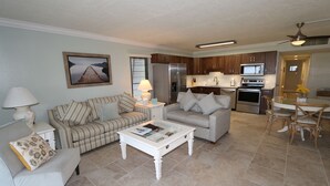 A living room with a sofa, armchair, and coffee table, a kitchen with appliances, and a dining area with chairs. - Cabana Beach Club by RVA (Longboat Key)