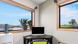 A corner office with a desk, computer, chair, potted plant, and a view of the parking lot. - SureStay Hotel by Best Western Manchester (Manchester)