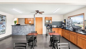 A modern kitchen with a dining area, featuring a ceiling fan, a microwave, a coffee machine, and a view of the outside. - SureStay Hotel by Best Western Manchester (Manchester)