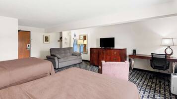 Une chambre d’hôtel avec deux lits, un canapé, une télévision, un bureau et une lampe.