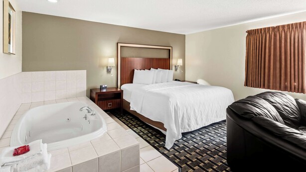 A hotel room with a large bed, a separate bathroom with a bathtub, and a leather sofa. - SureStay Hotel by Best Western Manchester (Manchester)