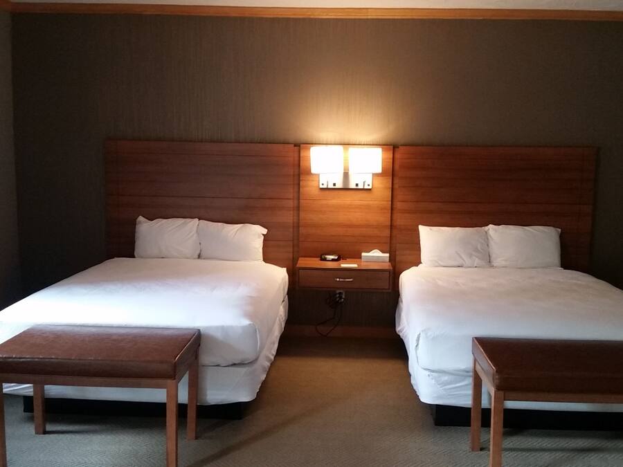Una habitación de hotel con dos camas, una mesita de noche y un escritorio.
