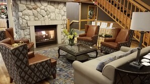 A cozy living room with a stone fireplace, leather armchairs, a sofa, and a coffee table.