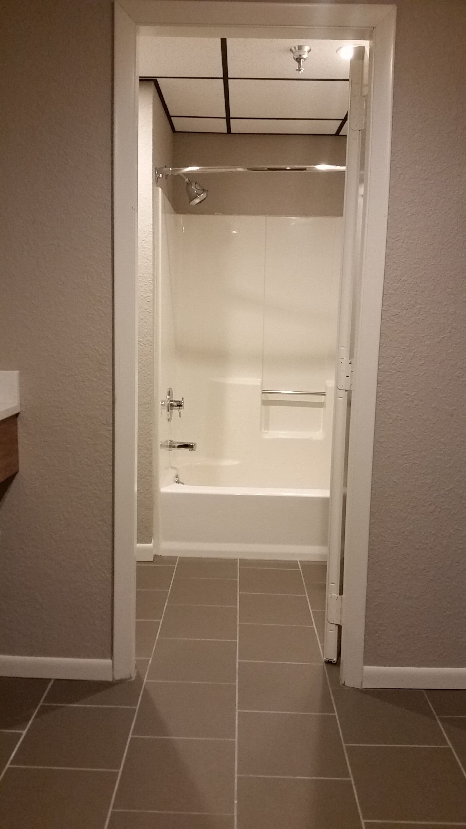 A walk-in shower with a glass door, a handheld showerhead, and a wall-mounted light fixture.