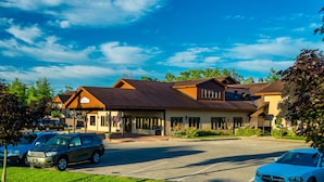 A hotel with a covered parking area, multiple buildings, and a clear blue sky.