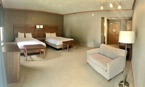 A hotel room with two beds, a sofa, a small table, and a lamp.