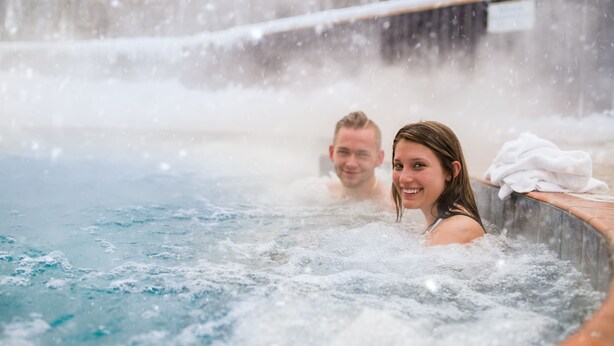 A hot tub with visible steam and a snowy background.