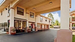 Ein zweistöckiges Motel mit überdachtem Parkplatz und Durchfahrtsfenster.