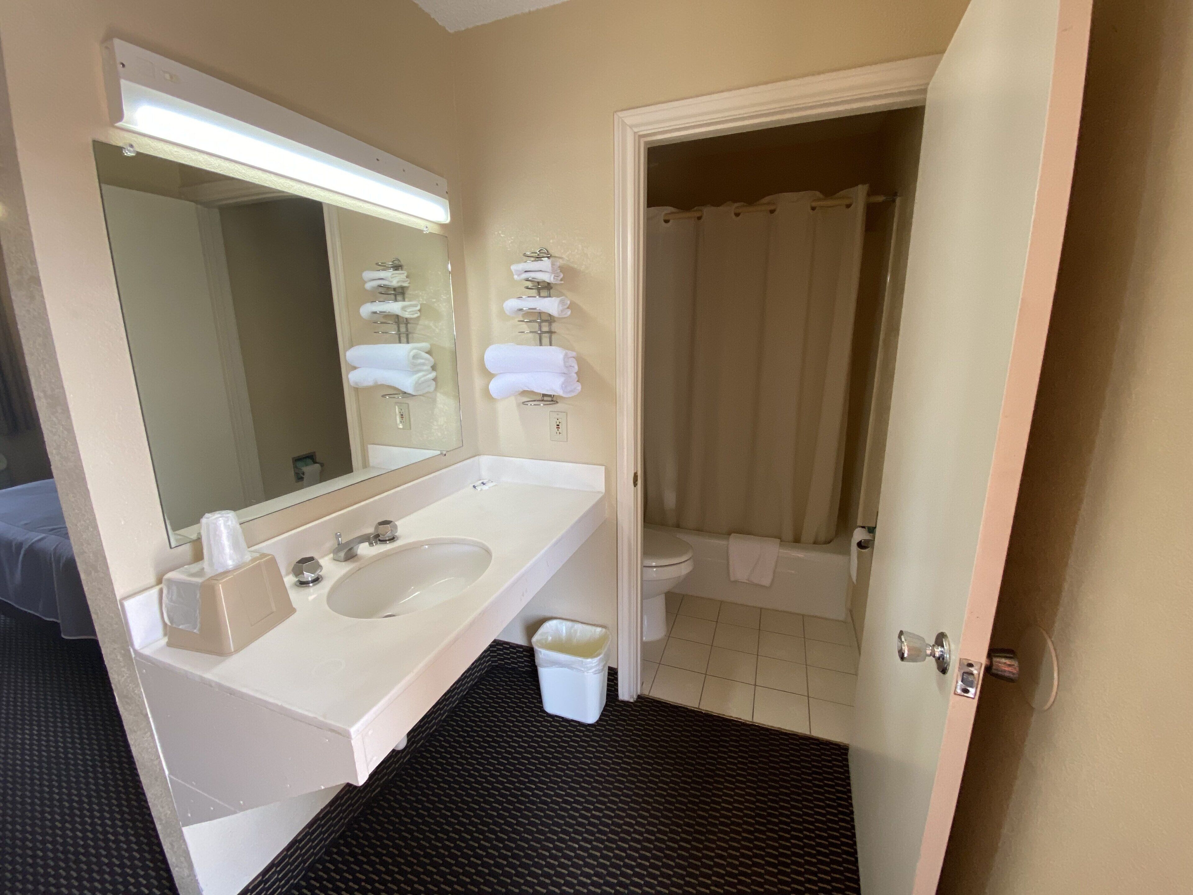 Un baño con lavamanos blanco, espejo y perchero.