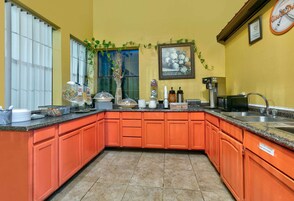 Una cocina con armarios color naranja, una cafetera y un reloj en la pared.
