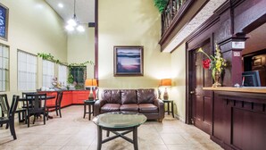 A spacious lobby with a dining area, a leather sofa, and a glass coffee table.