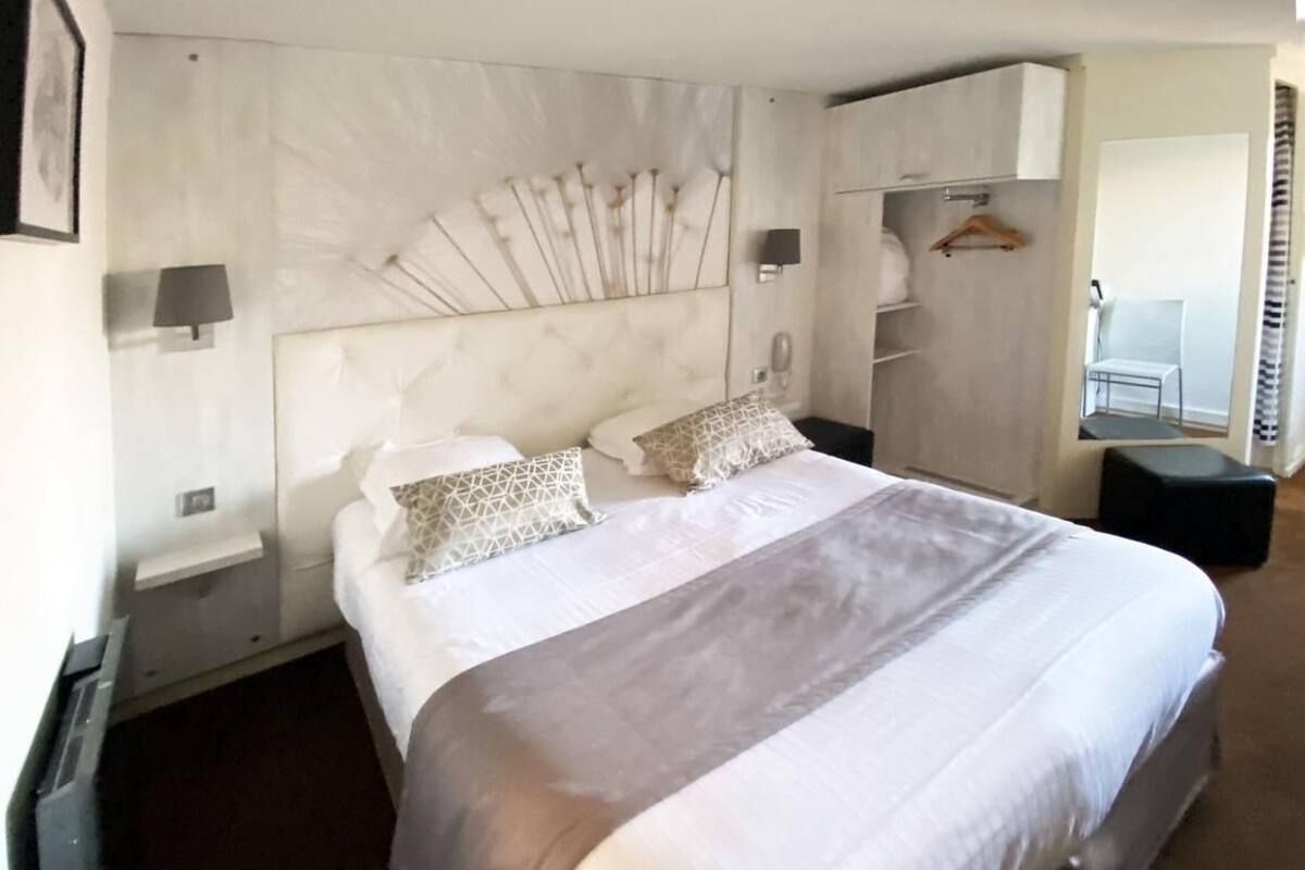 Ett hotellrum med en stor säng, en sänggavel med en unik design, ett sängbord och en garderob.