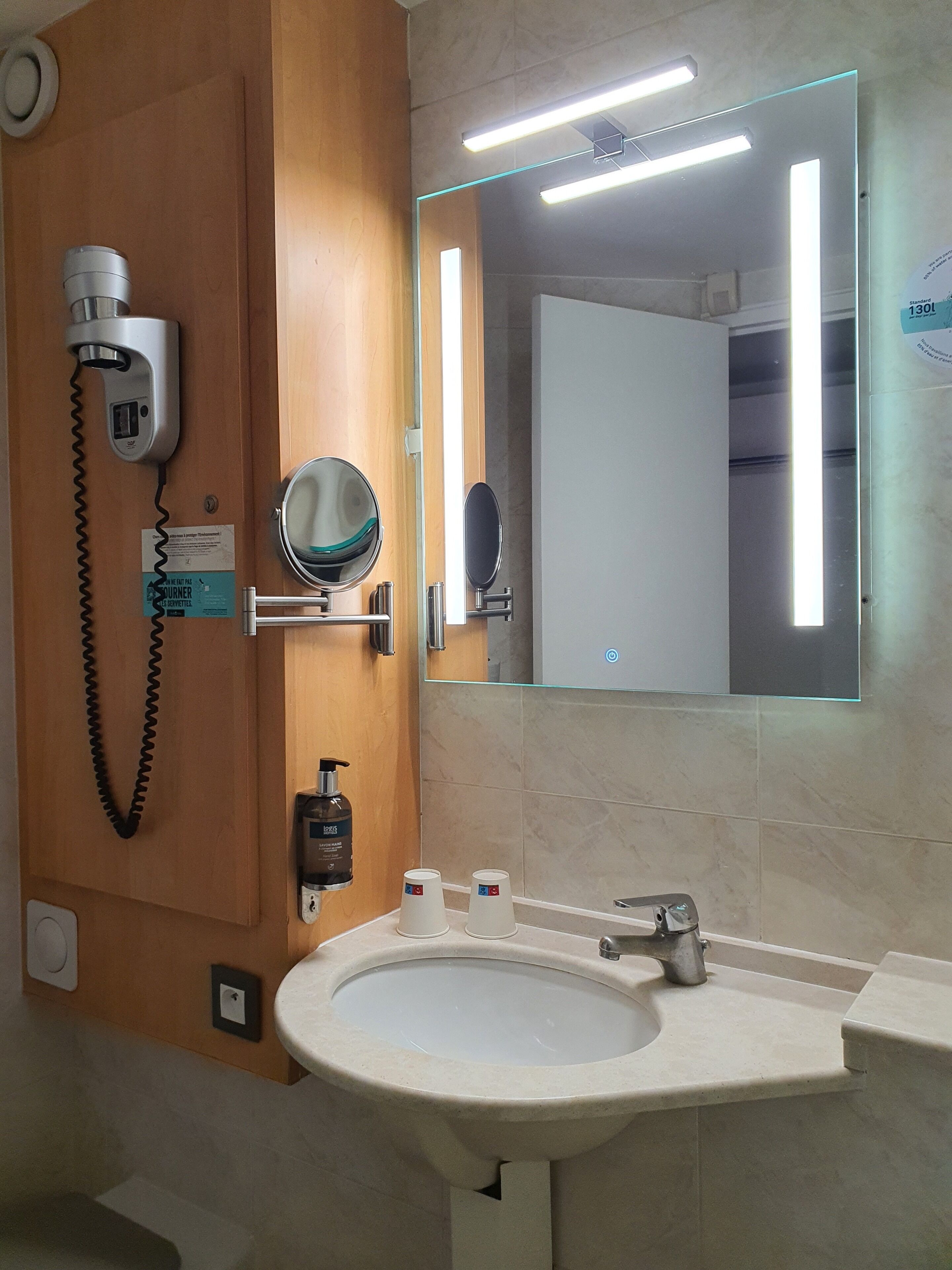 Un baño con lavamanos, espejo, secador de pelo y secador de manos.