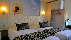 Ein Hotelzimmer mit zwei Betten, einem großen Wandbild und einem Holzschrank.