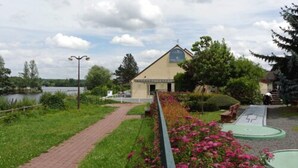 Ein Gebäude mit einem Glockenturm, einem gepflasterten Weg und einem kleinen Teich im Hintergrund.