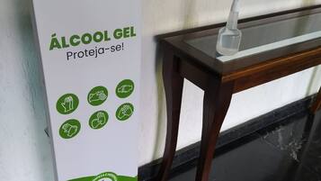 Un distributeur de gel hydroalcoolique vert et blanc, accompagné d’un mode d’emploi et d’un flacon de gel désinfectant pour les mains, est posé sur une table.