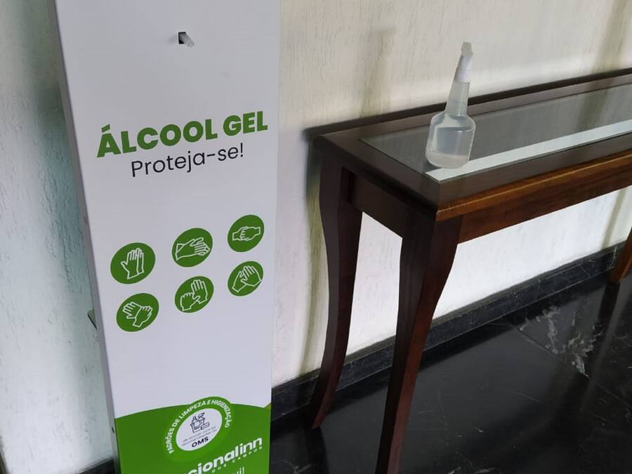 Un distributeur de gel hydroalcoolique vert et blanc, accompagné d’un mode d’emploi et d’un flacon de gel désinfectant pour les mains, est posé sur une table.