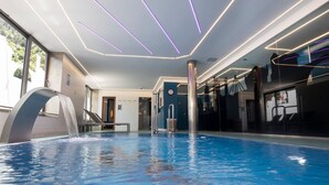 Een binnenzwembad met een modern design, inclusief een uniek waterkunstwerk en moderne verlichting.
