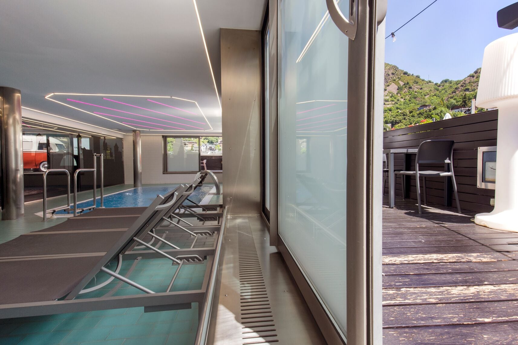 A pool area with sun loungers and a view of a hillside.