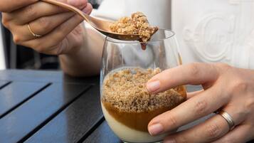 Una persona sosteniendo una cuchara con un postre, posiblemente un pudín, en un bol de vidrio.