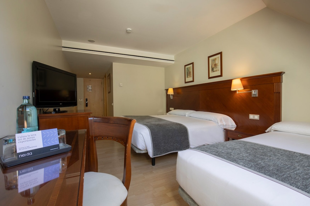 Een hotelkamer met twee bedden, een bureau met een computer, een televisie en een stoel.
