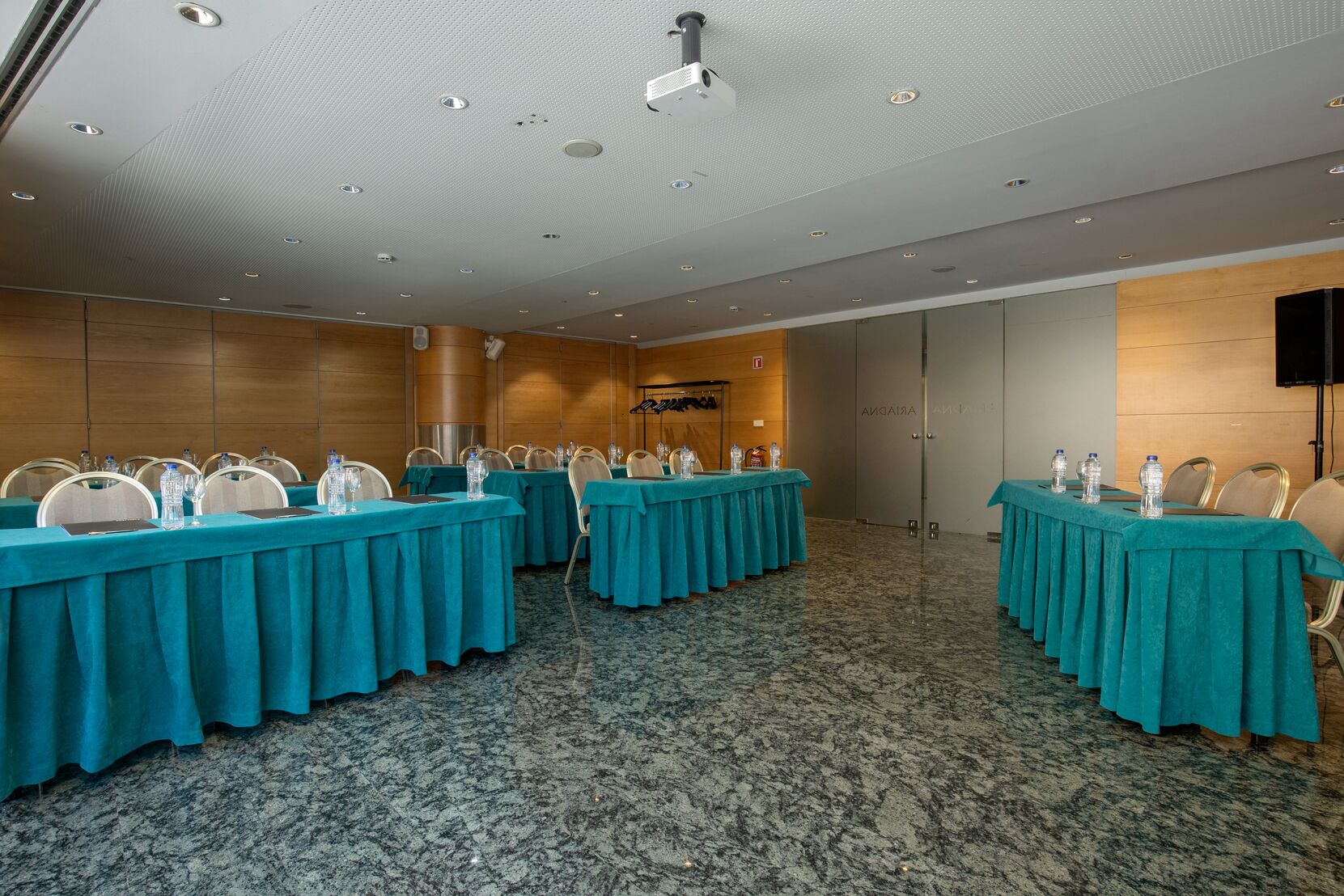 A conference room with multiple tables, chairs, and a projector screen.