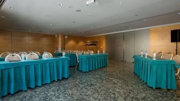A conference room with multiple tables, chairs, and a projector screen.
