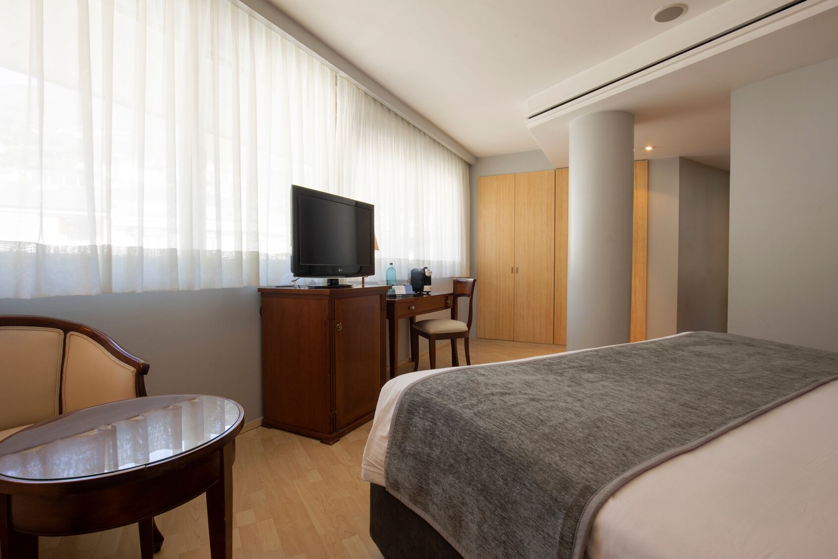 Ein Hotelzimmer mit einem Bett, einem Schreibtisch, einem Stuhl, einem Fernseher und einem Kleiderschrank.