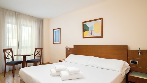 A hotel room with a large bed, two chairs, a small table, and artwork on the walls. -  Hotel Longoria Plaza by Pandora Hoteles (Oviedo)